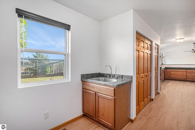 kitchen featuring a wealth of natural light, sink, light hardwood / wood-style floors, and a textured ceiling