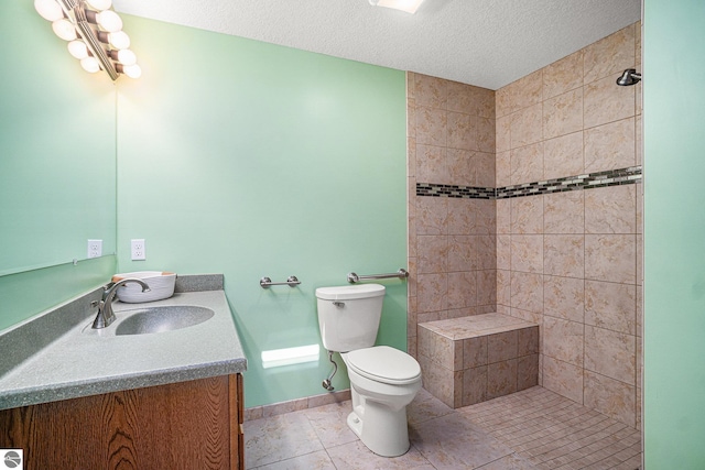 bathroom with tile patterned flooring, vanity, tiled shower, and toilet