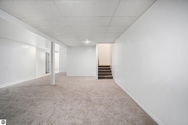 basement with a paneled ceiling and carpet