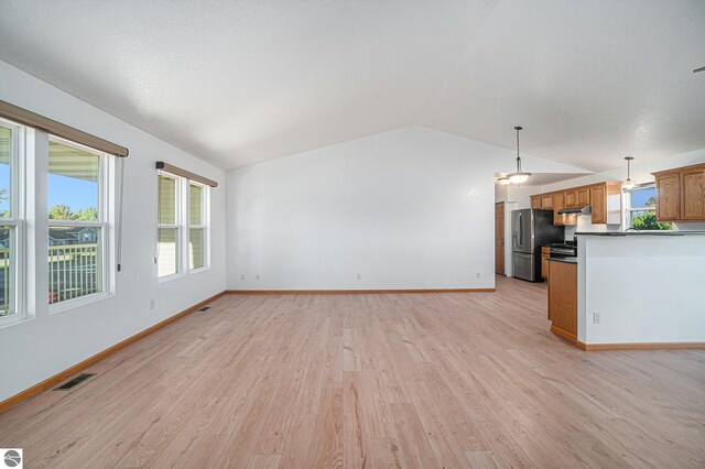 unfurnished living room with vaulted ceiling, light hardwood / wood-style flooring, and a textured ceiling