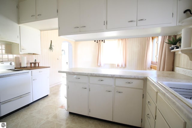 kitchen featuring white cabinets, decorative backsplash, and white stove