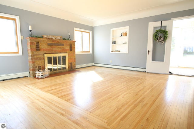 unfurnished living room with a brick fireplace, baseboard heating, built in features, and light hardwood / wood-style floors