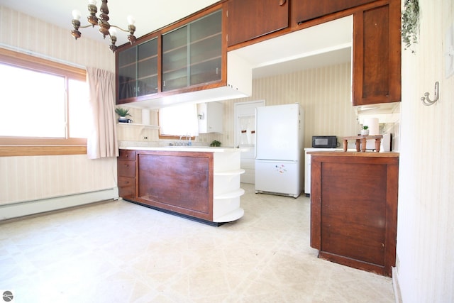 kitchen with white refrigerator, sink, a chandelier, and a baseboard heating unit