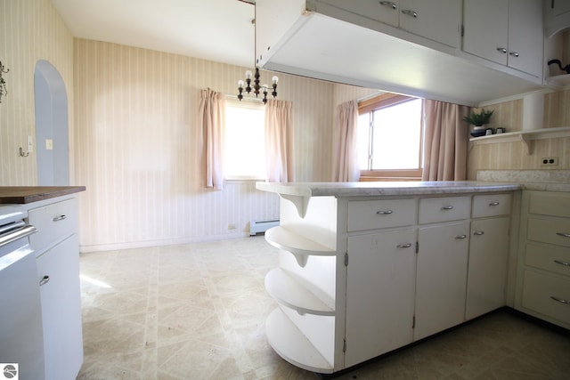 kitchen with decorative light fixtures, a baseboard heating unit, range, and white cabinetry