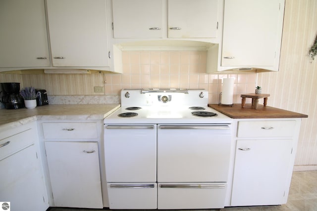 kitchen featuring electric stove, backsplash, and white cabinetry