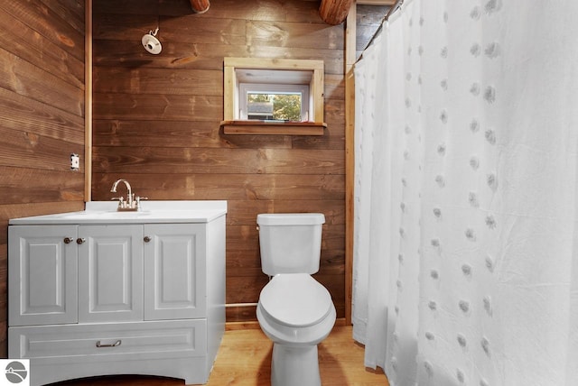 bathroom with vanity, wooden walls, toilet, and a shower with shower curtain