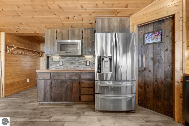 kitchen featuring stainless steel appliances, wooden ceiling, decorative backsplash, and wood walls