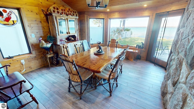 dining area featuring light hardwood / wood-style floors, lofted ceiling, and wooden walls