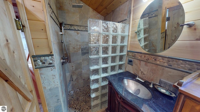 bathroom with vanity, a tile shower, and vaulted ceiling