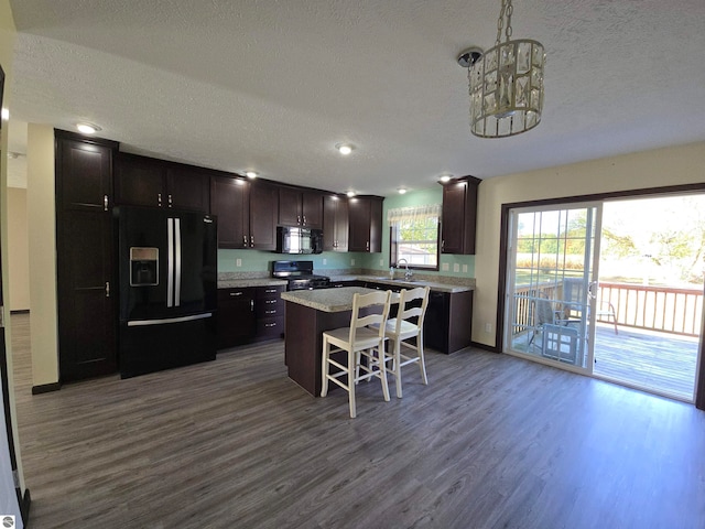 kitchen featuring black appliances, a center island, hardwood / wood-style flooring, sink, and a kitchen bar