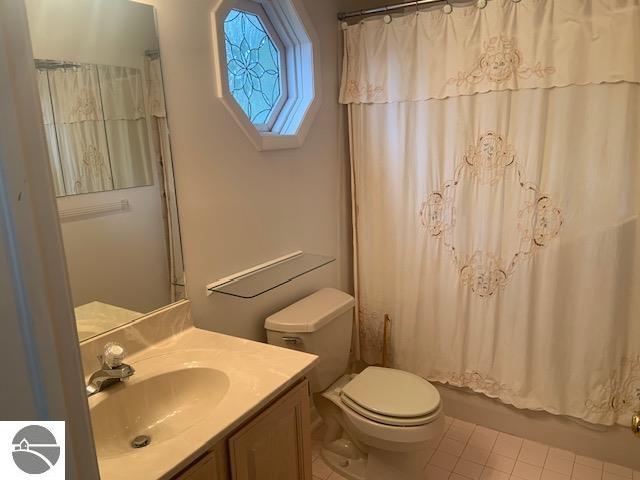 full bathroom with toilet, shower / tub combo, vanity, and tile patterned flooring