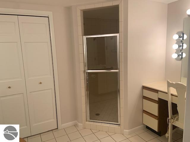 bathroom with a shower with door, vanity, and tile patterned floors