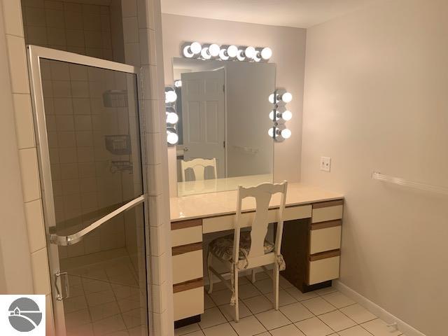 bathroom featuring vanity, a shower with shower door, and tile patterned flooring