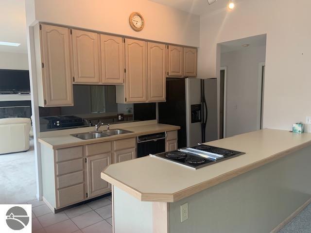 kitchen featuring light tile patterned floors, black appliances, sink, and kitchen peninsula