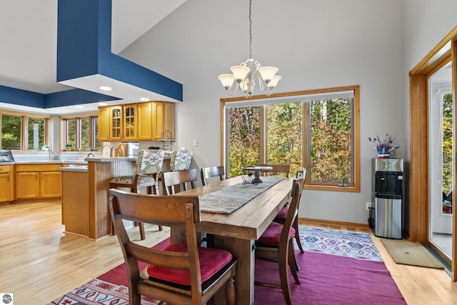 dining area featuring an inviting chandelier, a towering ceiling, and light hardwood / wood-style floors