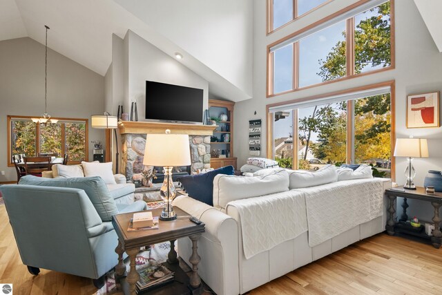 living room featuring high vaulted ceiling, a notable chandelier, and light wood-type flooring