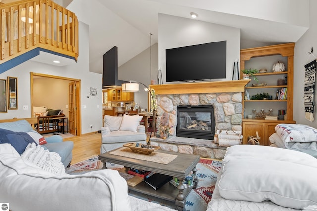 living room featuring high vaulted ceiling, a stone fireplace, and hardwood / wood-style floors