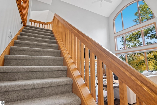 stairway with high vaulted ceiling and wood-type flooring