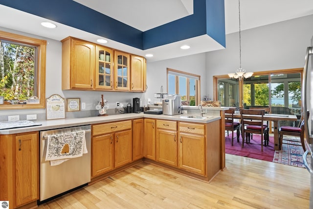 kitchen with light wood-type flooring, stainless steel dishwasher, kitchen peninsula, a notable chandelier, and decorative light fixtures