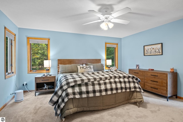 bedroom featuring light carpet, ceiling fan, and a textured ceiling