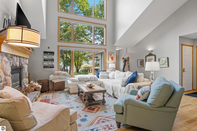 living room with a fireplace, a towering ceiling, and wood-type flooring