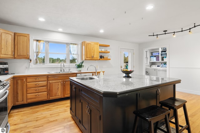 kitchen with light hardwood / wood-style flooring, sink, and a kitchen island with sink