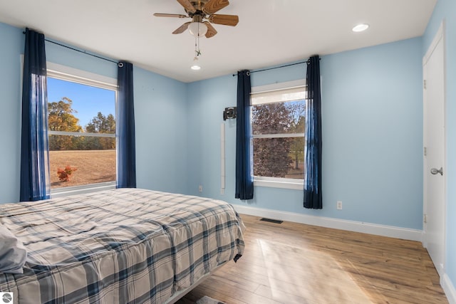 bedroom featuring ceiling fan, multiple windows, and light wood-type flooring