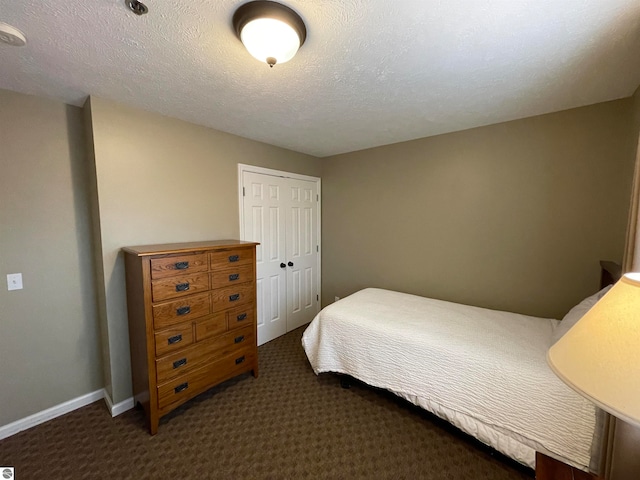 bedroom with dark colored carpet, a closet, and a textured ceiling