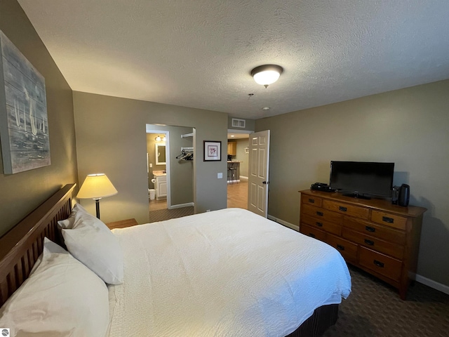 carpeted bedroom featuring connected bathroom and a textured ceiling