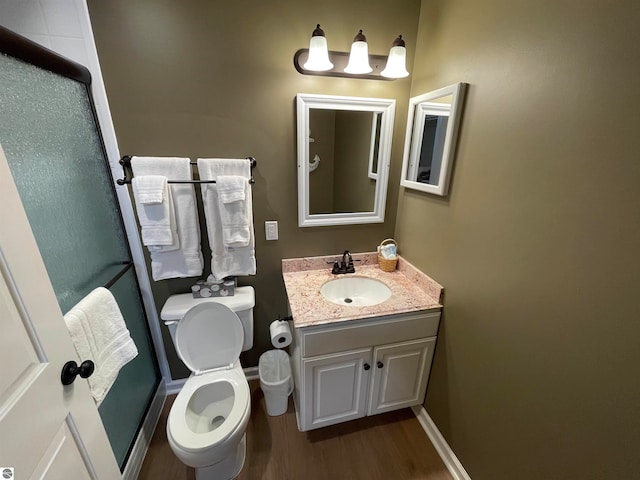 bathroom with hardwood / wood-style floors, an enclosed shower, vanity, and toilet