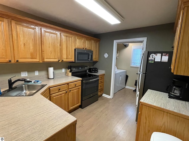 kitchen with black / electric stove, light hardwood / wood-style flooring, sink, and washing machine and dryer