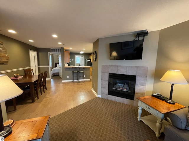 living room featuring light wood-type flooring and a tile fireplace