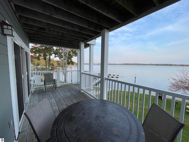 wooden terrace with a water view and a yard