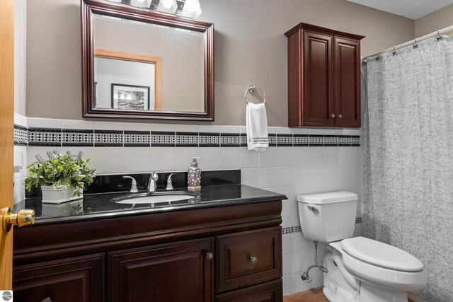 bathroom with vanity, tile walls, and toilet