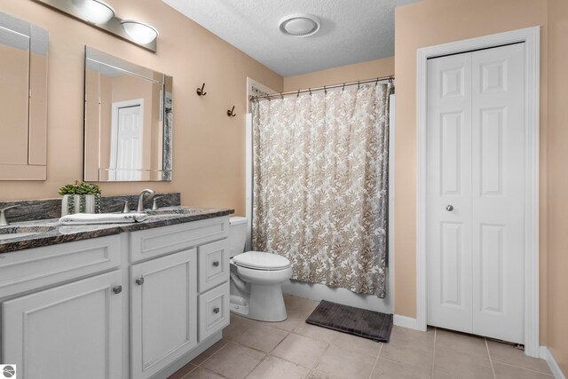 bathroom featuring vanity, a shower with shower curtain, tile patterned flooring, toilet, and a textured ceiling