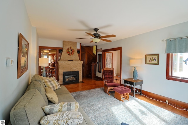 living room with a brick fireplace, hardwood / wood-style flooring, and ceiling fan