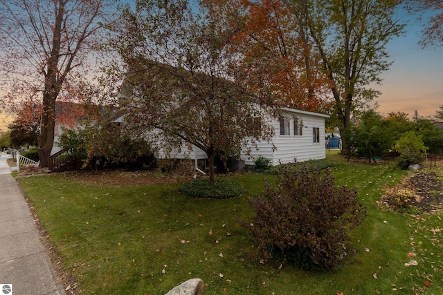 property exterior at dusk featuring a yard