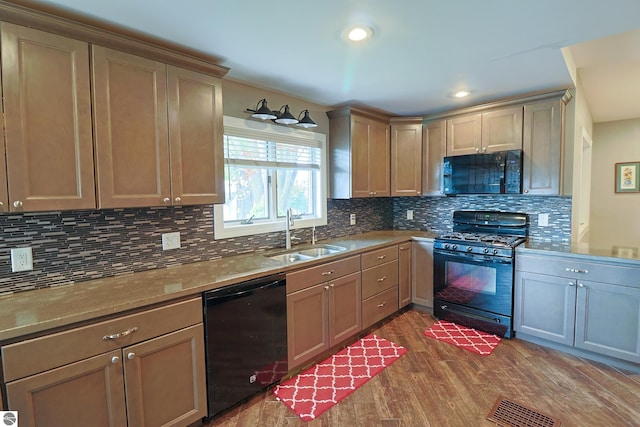 kitchen featuring sink, tasteful backsplash, stone countertops, dark wood-type flooring, and black appliances