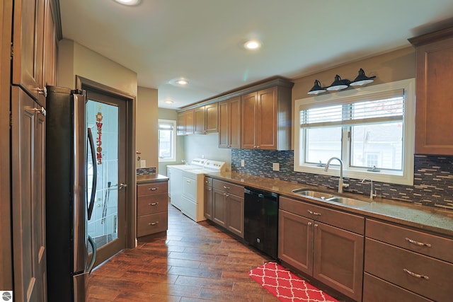 kitchen with stainless steel refrigerator, washer and clothes dryer, dark wood-type flooring, sink, and dishwasher