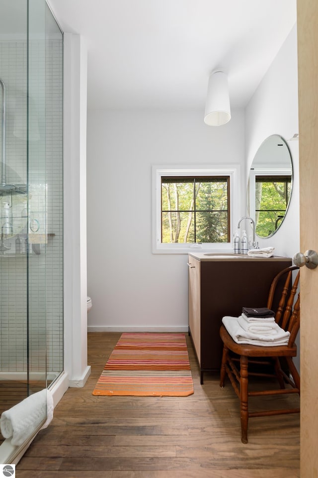 bathroom with an enclosed shower, hardwood / wood-style flooring, vanity, and toilet