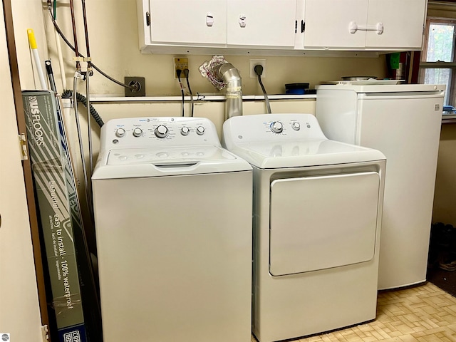 laundry room featuring washer and dryer and cabinets