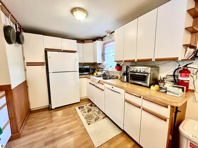 kitchen featuring sink, white appliances, white cabinetry, and light hardwood / wood-style floors