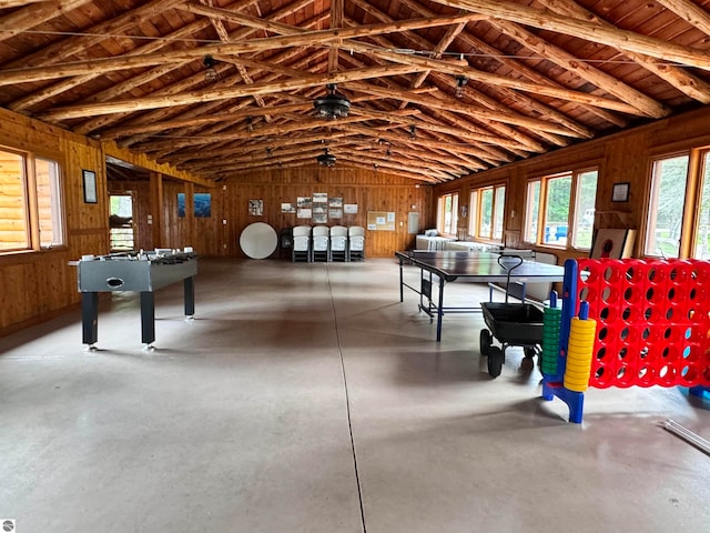 playroom with wooden walls, vaulted ceiling with beams, wood ceiling, and concrete flooring