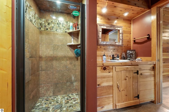 bathroom with wooden walls, tiled shower, vanity, and wood ceiling