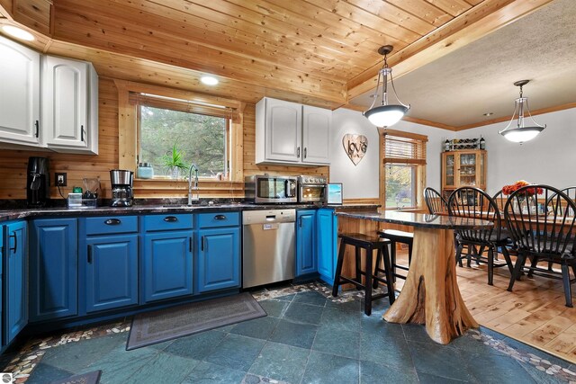 kitchen with pendant lighting, wood-type flooring, white cabinetry, blue cabinetry, and stainless steel appliances