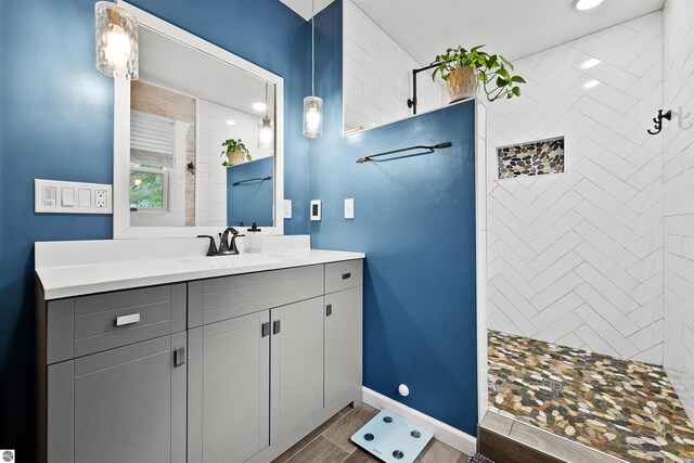 bathroom with vanity, hardwood / wood-style flooring, and tiled shower