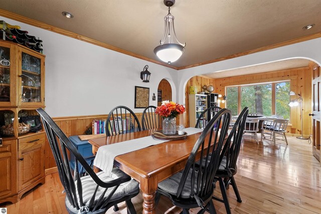 dining area featuring wood walls, light hardwood / wood-style floors, and crown molding