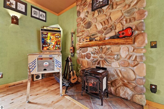 details featuring ornamental molding, hardwood / wood-style floors, and a wood stove