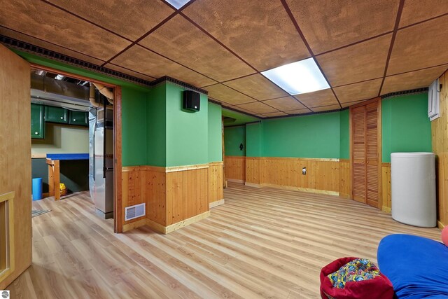 basement featuring wooden walls and light hardwood / wood-style floors