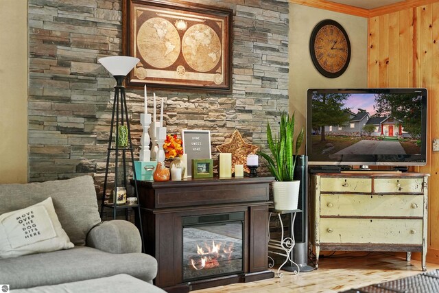 living room with a stone fireplace, hardwood / wood-style floors, and ornamental molding